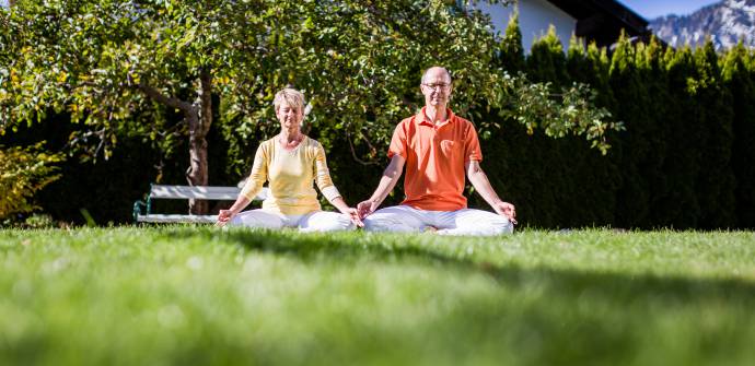 Mann und Frau beim Meditieren im Garten