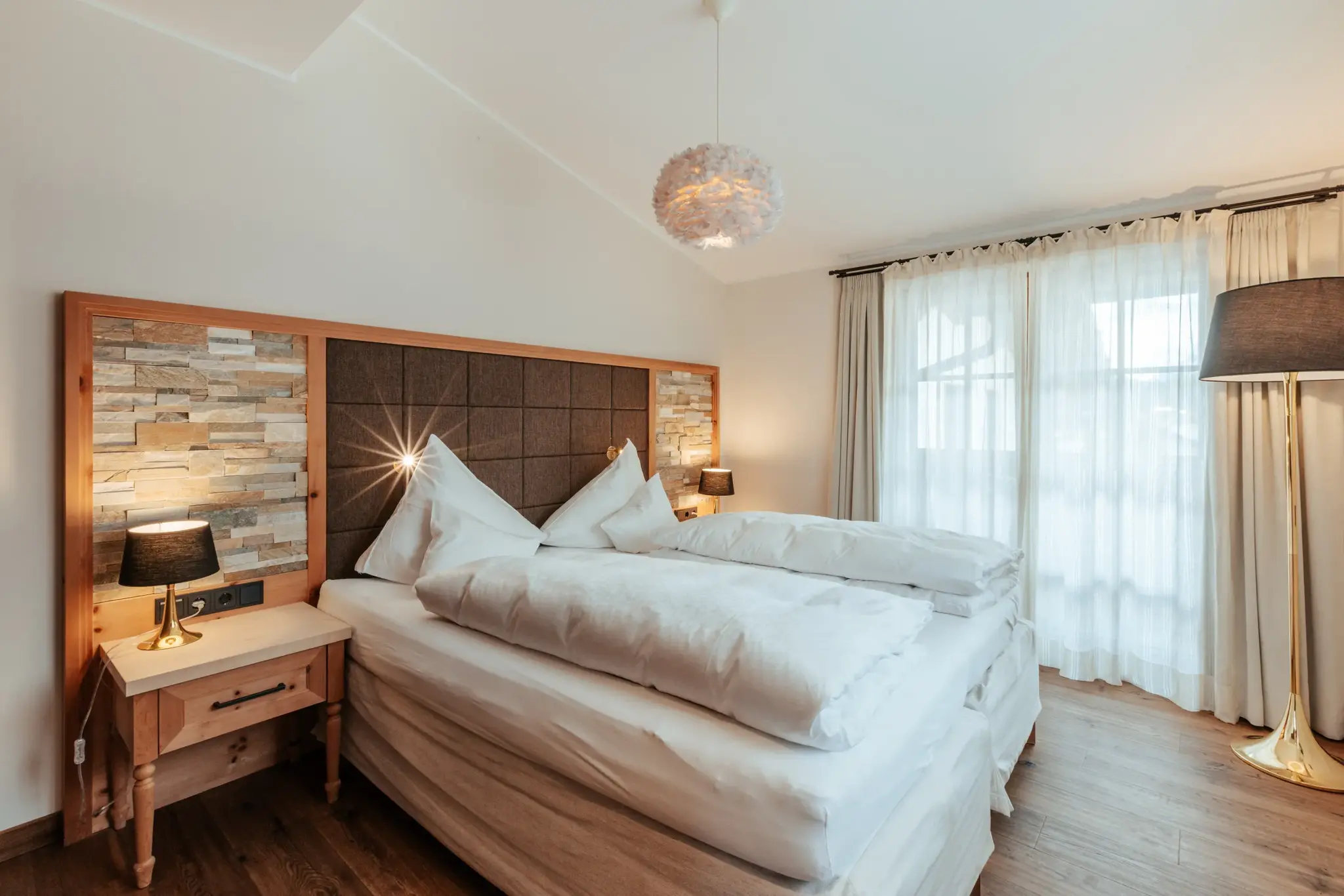 Gemütliches Biozimmer Alpin mit Natursteinwand, warmem Holz und Balkon — Urlaubsangebote des Biohotel Schweitzer in Mieming, Tirol