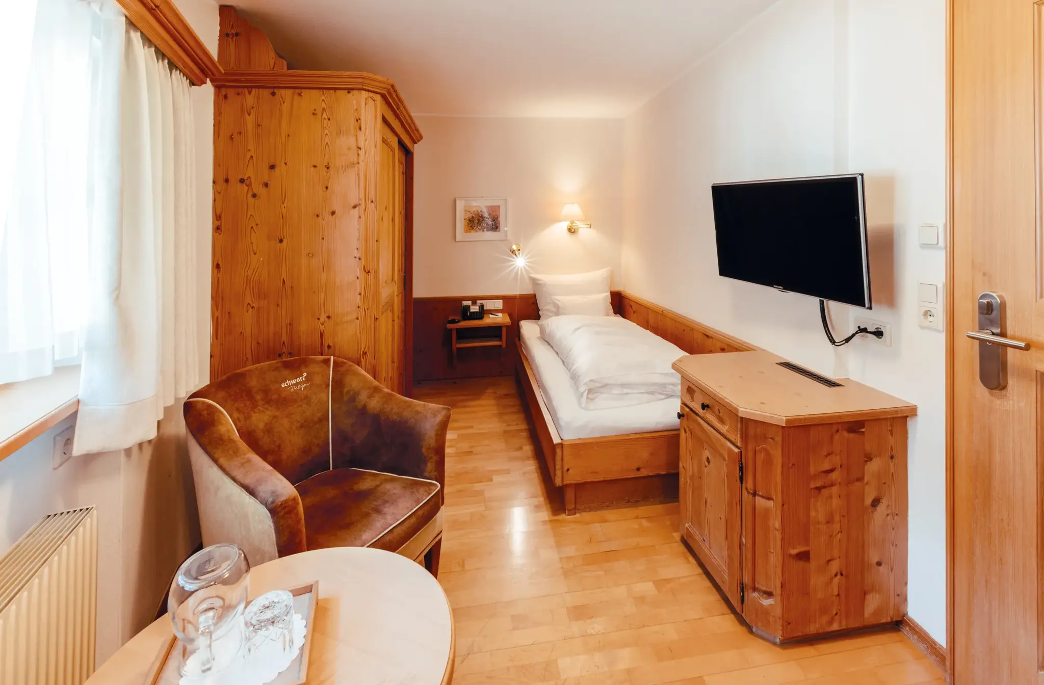 Einzelzimmer Basic mit Zirbenholz-Schrank, Einzelbett und Ledersessel im Biohotel Schweitzer in Mieming