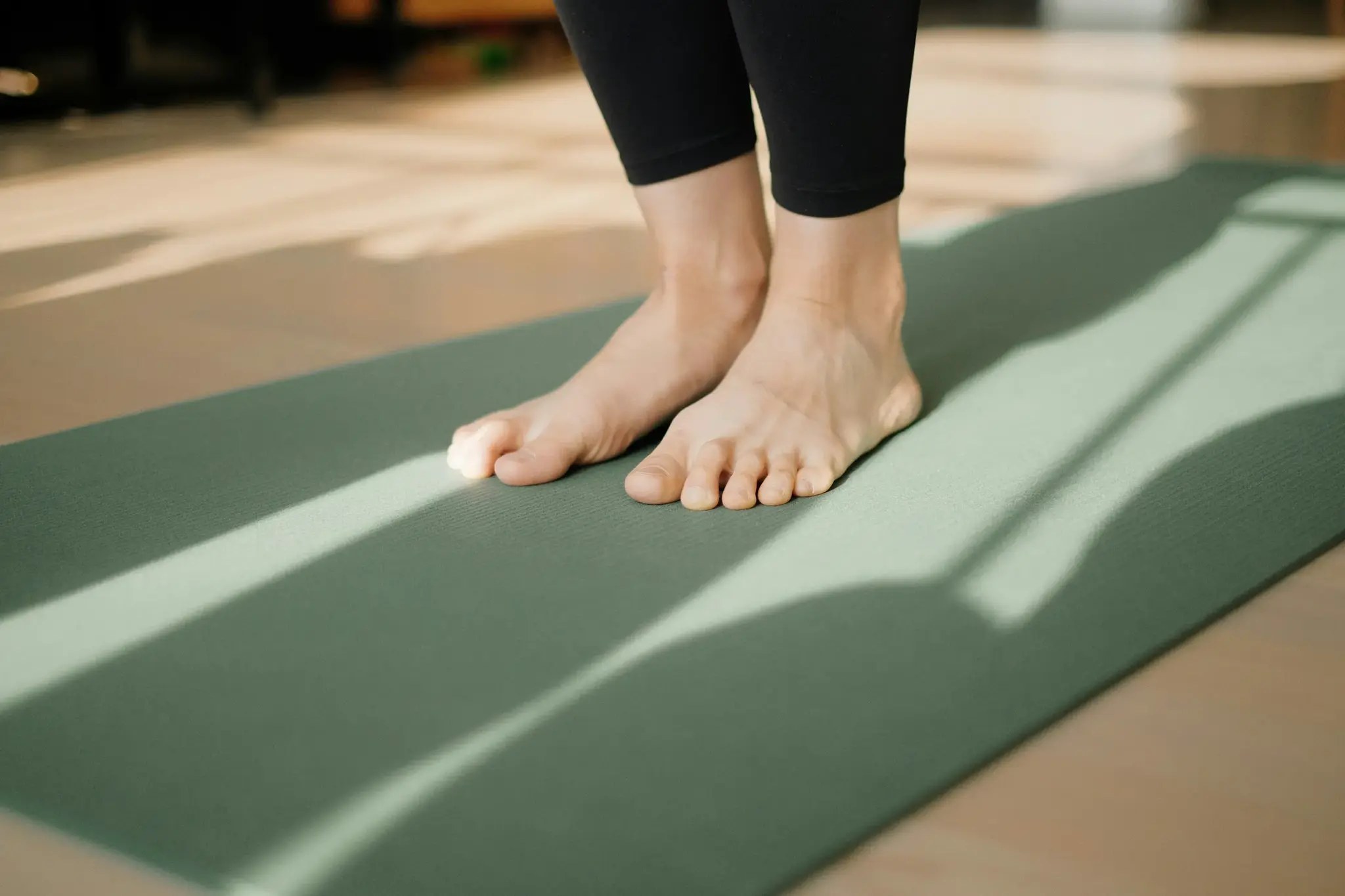 Barfuß auf grüner Yogamatte im sonnendurchfluteten Raum beim Yoga-Retreat im Biohotel Schweitzer