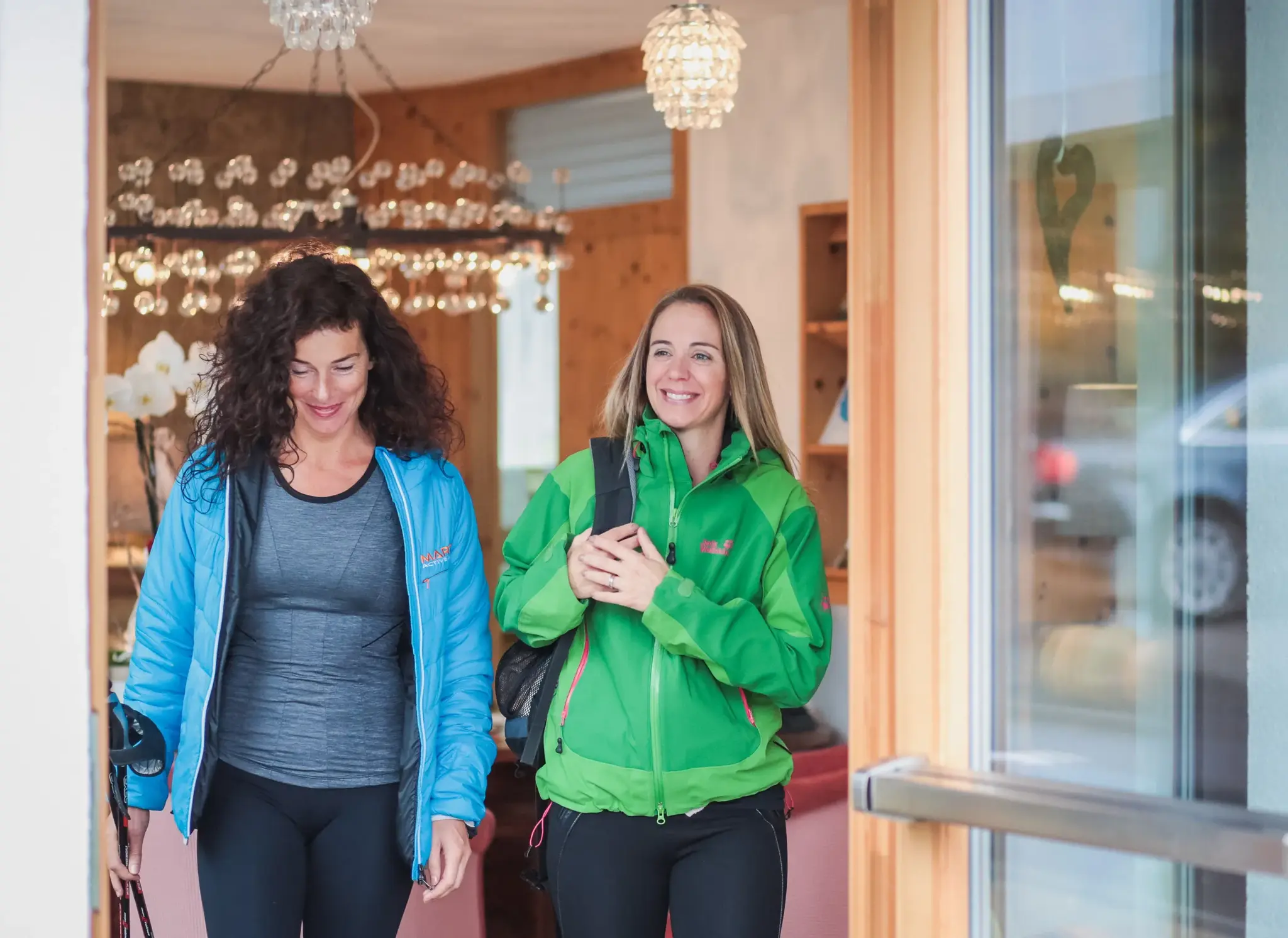 Two women in sportswear with hiking poles setting off for a fasting hike — active therapeutic fasting at Biohotel Schweitzer