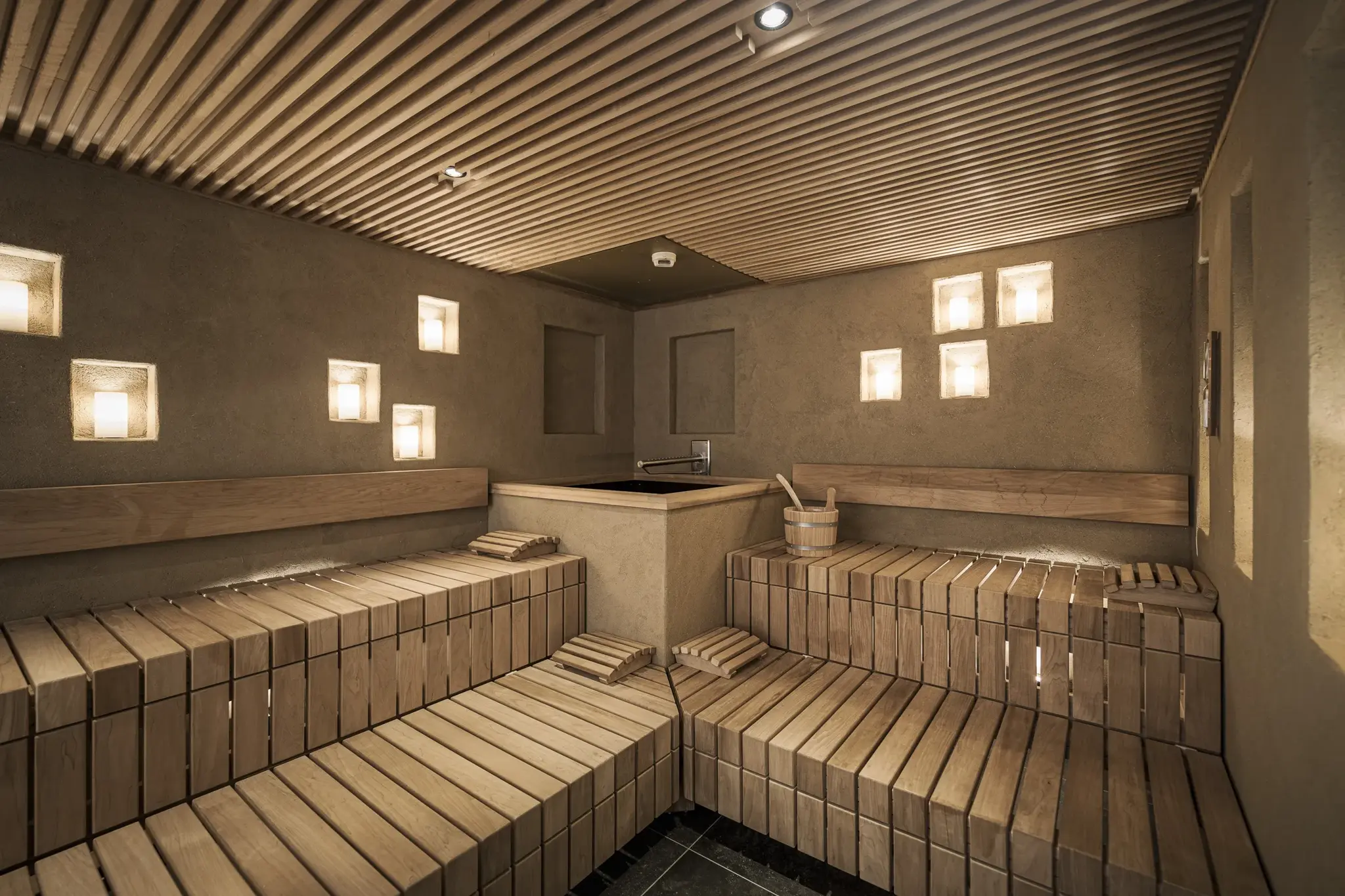 Warm sauna with wooden benches and candlelit niches in the Day Spa at Alpenresort Schwarz