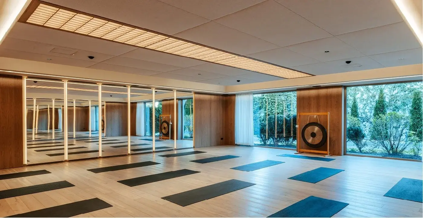 Yogastudio im Bloom Floor des Alpenresort Schwarz mit Spiegelwand, Matten und Gong vor der Glasfront zum Garten