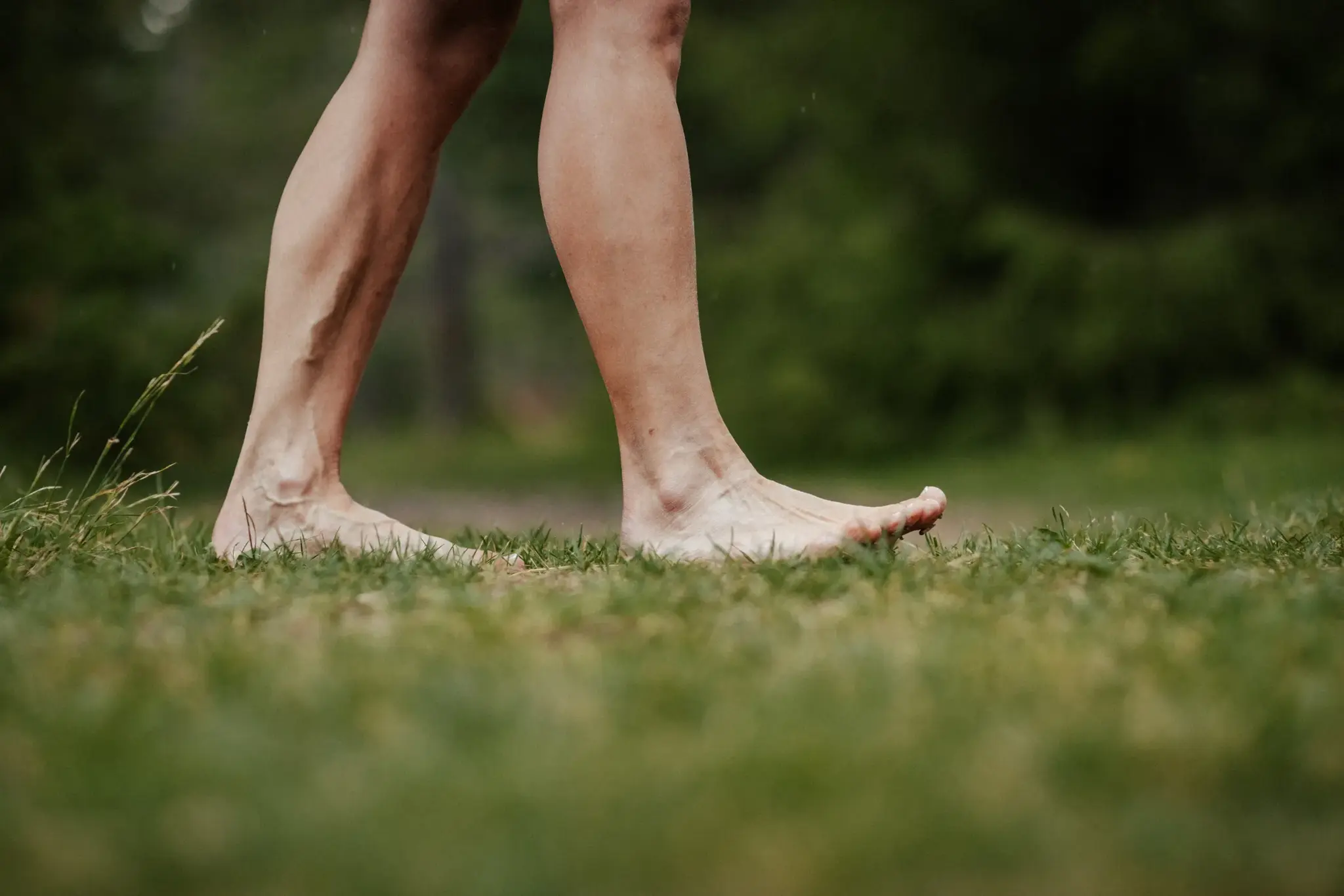 Walking barefoot across a green summer meadow during a yoga retreat in nature near Mieming, Tyrol