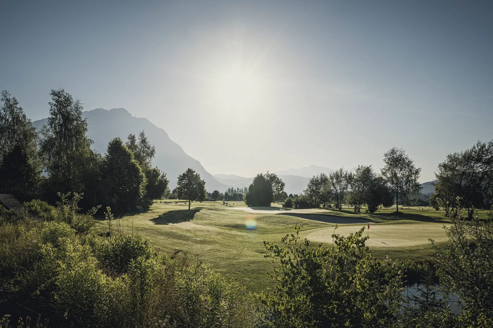 Sonniger Golfplatz des Alpenresort Schwarz mit Grün, Bunker und Bergpanorama am Mieminger Plateau in Tirol