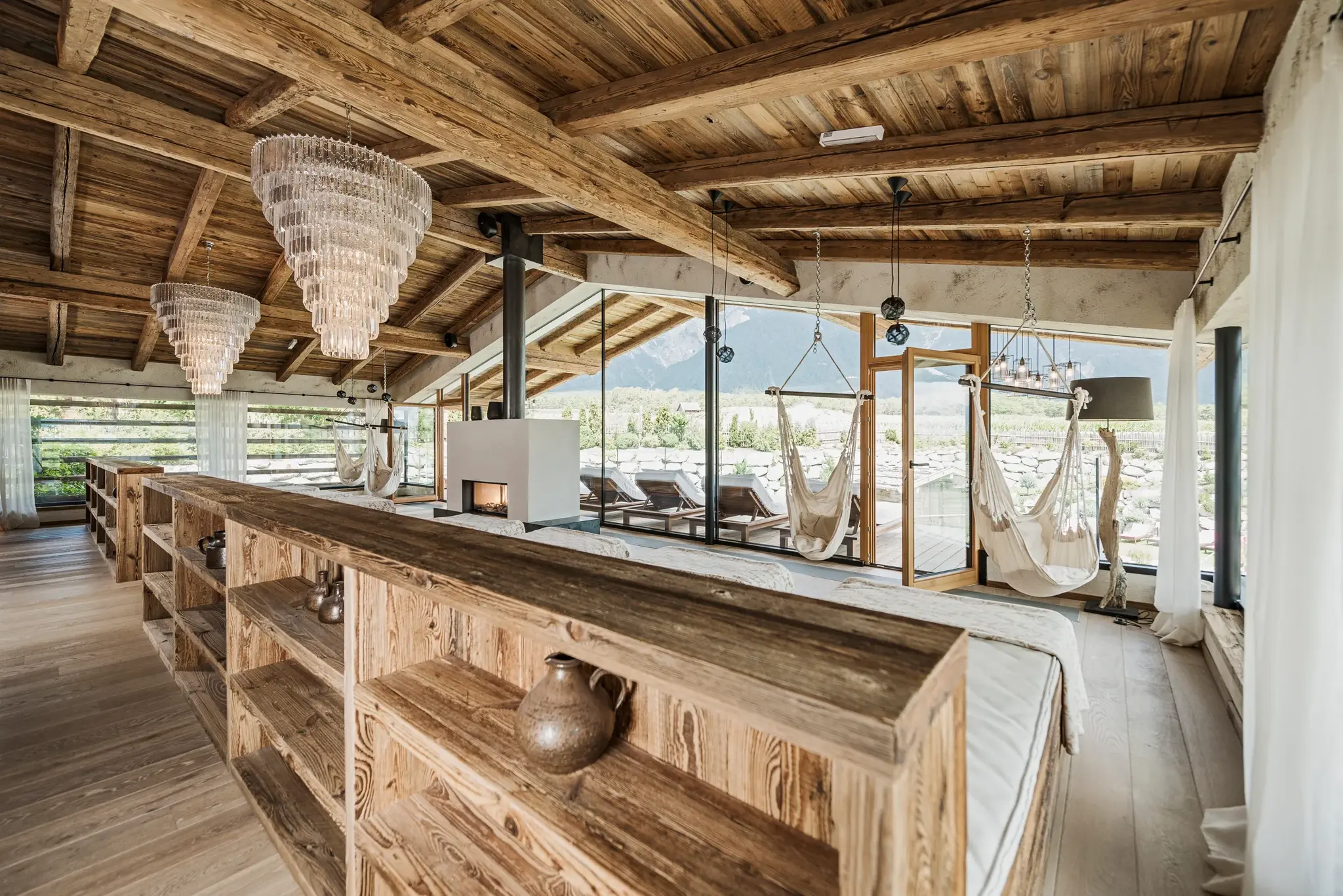 Ruheraum mit hängenden Liegen aus Altholz, Kamin und Panoramablick auf die Tiroler Berge im Day Spa des Alpenresort Schwarz